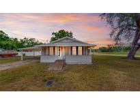 Charming single-story home featuring a cozy screened porch, carport, and a picturesque sunset backdrop at 410 Orange St, Bradley, FL 33835