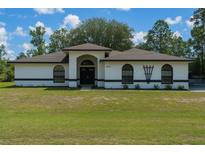 Charming single-story home boasts a well-manicured front lawn, arched entryway, and neutral-toned exterior at 5218 Parkland Ct, Lakeland, FL 33811