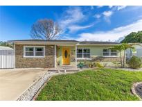 Charming single-story home featuring a stone facade, a well-manicured lawn, and a bright yellow front door at 1210 Marrick Cir, Lakeland, FL 33815