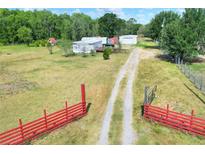 Open property showcasing the home's access to nature and various structures and the red post and plank fence at 14810 Brahma Rd, Polk City, FL 33868