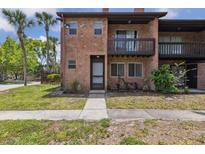 Charming brick condo with a cozy balcony, lush landscaping, and sidewalk leading to the front entrance at 2369 Tom Jones St # 8, Orlando, FL 32839