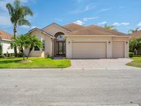 Charming home with a three-car garage, well-manicured lawn, and lush landscaping including mature palm trees at 4193 Stone Creek Loop, Lake Wales, FL 33859