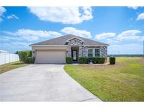 Charming single-story home featuring a stone-accented facade, manicured landscaping, and a two-car garage at 3560 Spring Creek Rd, Dundee, FL 33838
