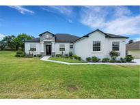 Beautiful one-story home with white exterior, dark roof, manicured lawn and elegant stone accents at 3664 Frentress Dr, Lakeland, FL 33812