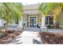 Inviting home entrance featuring double glass doors and a covered porch framed by palm trees at 4540 Park Ave, Indian Lake Estates, FL 33855