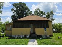 A charming home exterior showing a screened front porch under a sunny, partly cloudy sky at 4885 Cherry Dr, Mulberry, FL 33860