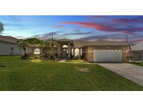 Charming single-story home featuring a well-manicured lawn, attached garage, and inviting curb appeal at sunset at 4965 Tradition Dr, Lakeland, FL 33812