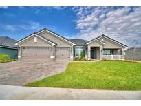 Beautiful single-Gathering home featuring a well-manicured lawn and a three-car garage with a brick paver driveway at 5220 Tennessee Ridge Ct, Auburndale, FL 33823
