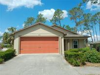 Charming single-story home with a well-manicured lawn and a two-car garage with an orange door at 7952 Grand Pines Blvd, Lakeland, FL 33810