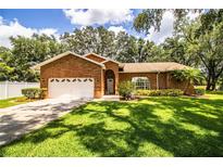 Charming brick home featuring a well-manicured lawn, attached garage, and inviting front entrance at 909 Lake Deeson Pt, Lakeland, FL 33805