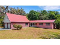 Charming brick home with a red metal roof, attached garage, and covered porch on a sunny lot at 3822 Charter Rd, Lakeland, FL 33810