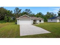 Charming single-story home with a two-car garage, landscaped yard, and a long concrete driveway at 10470 Sw 139Th Ct, Dunnellon, FL 34432