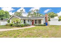 Charming single-story home featuring a red door, brick chimney, and mature landscaping at 1421 Camphor Dr, Lakeland, FL 33803