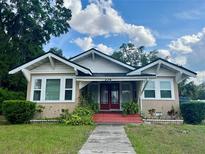 Charming bungalow-style home featuring a front yard with plants, a red front porch, and beautiful architectural details at 236 E Seminole Ave, Lake Wales, FL 33853