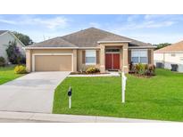 Charming one-story home with a well-manicured lawn, attached garage, and inviting red front door at 4041 Byrds Crossing Dr, Lakeland, FL 33812