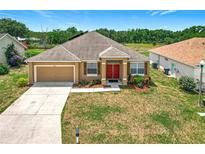 Charming single-story home with a well-maintained lawn, attached garage, and vibrant red front door at 4041 Byrds Crossing Dr, Lakeland, FL 33812