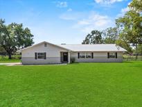 Charming single-story home with a well-manicured lawn and a classic, neutral-toned facade at 511 Hickory Hammock Rd, Lake Wales, FL 33859