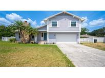 Charming two-story home featuring light-gray siding, a stone chimney, and lush palm trees in the front yard at 707 Laurel Pointe Ct, Lakeland, FL 33813