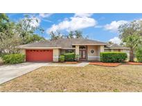 Charming one-story home with a red garage door and manicured landscaping at 7741 Merrily Way, Lakeland, FL 33809