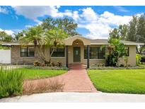 Charming single-story home with brick walkway, lush lawn, beautiful tropical landscaping, and inviting front entrance at 865 E Mann Rd, Bartow, FL 33830