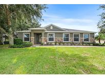 Charming home with stone accents, well-manicured lawn, and lush landscaping creating great curb appeal at 1001 Lena Run Ct, Winter Haven, FL 33880