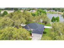 Waterfront home with lush greenery, a black roof, and an attached two-car garage at 1837 Farrington Dr, Lakeland, FL 33809