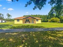 Sunny single story home with a small covered patio and green lawn at 2323 State Road 33, Clermont, FL 34714