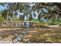 Charming one-story brick home featuring an inviting front yard with mature trees and a sidewalk at 415 Manor Dr, Bartow, FL 33830