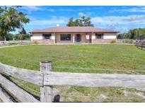 Charming single-story home with a metal roof, brick accents, a fenced yard and a vibrant green lawn at 4404 Musket Dr, Lakeland, FL 33810