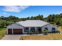 Charming single-story home featuring a metal roof, a well-maintained lawn, a two-car garage, and a cozy front porch at 1 Brogden Se Ct, Winter Haven, FL 33880
