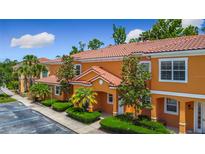 Charming condo with a Spanish tile roof, orange stucco, mature landscaping, and assigned parking at 2683 Corvette Ln, Kissimmee, FL 34746
