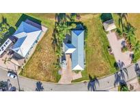 An aerial view of a charming home with a blue metal roof, lush landscaping, and brick-paved driveway at 3016 Wood Duck Dr, Polk City, FL 33868