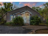 Charming single-story home with a quaint front porch and beautiful brick driveway at sunset at 402 W Patterson St, Lakeland, FL 33803