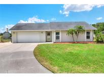 Charming single-story home with a well-manicured lawn, palm trees, and a driveway leading to an attached garage at 404 Willow Run, Lakeland, FL 33813