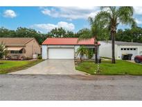 Charming single-story home with a well-manicured lawn, mature palm trees, and a red tiled roof at 409 San Jose Dr, Winter Haven, FL 33884