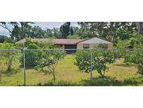 Ranch-style house with a charming tan exterior, well-maintained lawn, and mature trees around the property at 5211 Berkley Rd, Auburndale, FL 33823