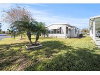 Bright home featuring manicured lawn, a carport, and decorative palm trees at 6087 Southern Oaks Se Dr, Winter Haven, FL 33884