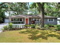 Charming one-story home boasts a well-maintained lawn, mature trees, and an inviting orange front door at 618 W Oak Dr, Lakeland, FL 33803