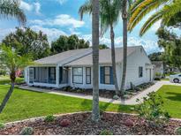 Charming single-story home with white siding, manicured lawn, and mature palm trees adding to the curb appeal at 6194 Sanderling Dr, Lakeland, FL 33809