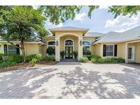 Elegant single-story home featuring a grand entrance, lush landscaping, and a spacious circular driveway at 645 Whisper Woods Dr, Lakeland, FL 33813
