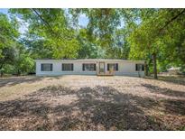 Charming single story home with black shutters and a wooden porch nestled amongst mature trees at 6527 Fernwood Dr, Lakeland, FL 33810