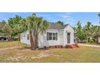 Charming home featuring a well-kept lawn and a white exterior, complemented by vibrant palm trees at 725 Avenue B Sw, Winter Haven, FL 33880