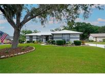 Charming single-story home with a manicured lawn, mature tree, and welcoming curb appeal on a sunny day at 8760 Plantation Ridge Blvd, Lakeland, FL 33809