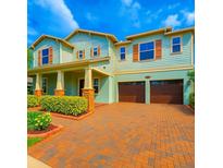 Charming two-story home features a brick driveway, two-car garage, and inviting front porch with columned supports at 13525 Gorgona Isle Dr, Windermere, FL 34786