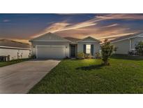 Charming single-story home with neutral siding, attached garage, and manicured lawn under a colorful sky at 1725 Hill Top Dr, Dundee, FL 33838