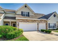 Charming townhome featuring a stone facade, attached two-car garage, and well-maintained landscaping at 2047 Winterset Dr, Lakeland, FL 33813