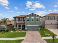 Two-story home boasts an attached two-car garage, brick-paved driveway, and lush landscaping at 2317 Bella Luna Cir, Lakeland, FL 33810