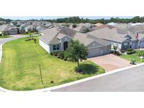 Aerial view of single-story home showcases its well-kept lawn, landscaping, and brick driveway leading to a garage at 3136 Langdon Ln, Winter Haven, FL 33884