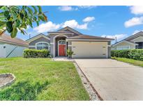 Charming single-story home with a well-manicured lawn, neutral paint, and an attached two-car garage at 420 Sir Phillips Dr, Davenport, FL 33837