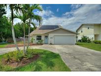 Charming single-story home featuring a two-car garage, solar panels, well-maintained landscaping, and palm trees at 440 Lake Daisy, Winter Haven, FL 33884